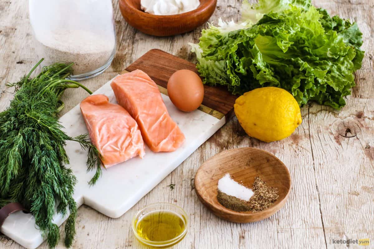 Ingredients on a table including salmon, lemon, lettuce, olive oil, almond flour, egg, herbs and spices