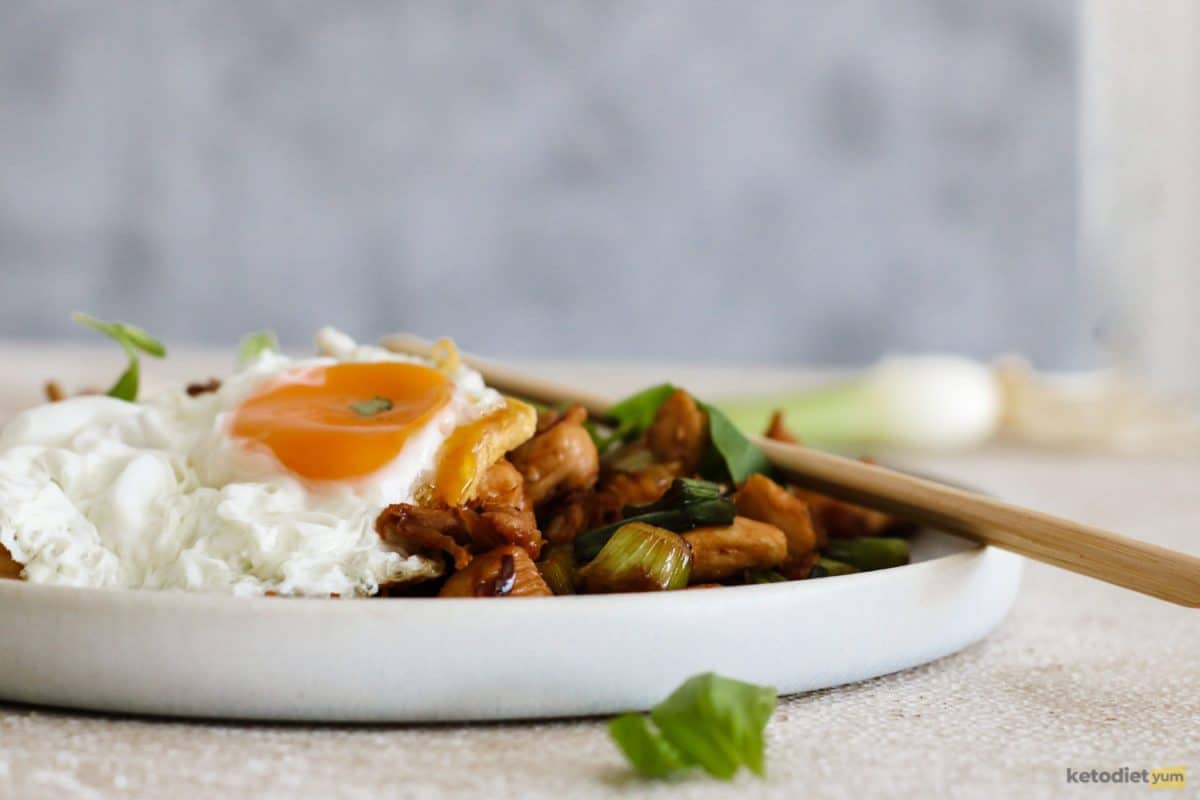 Keto Thai basil chicken recipe served with a fried egg sunny side up on a white plate with chopsticks