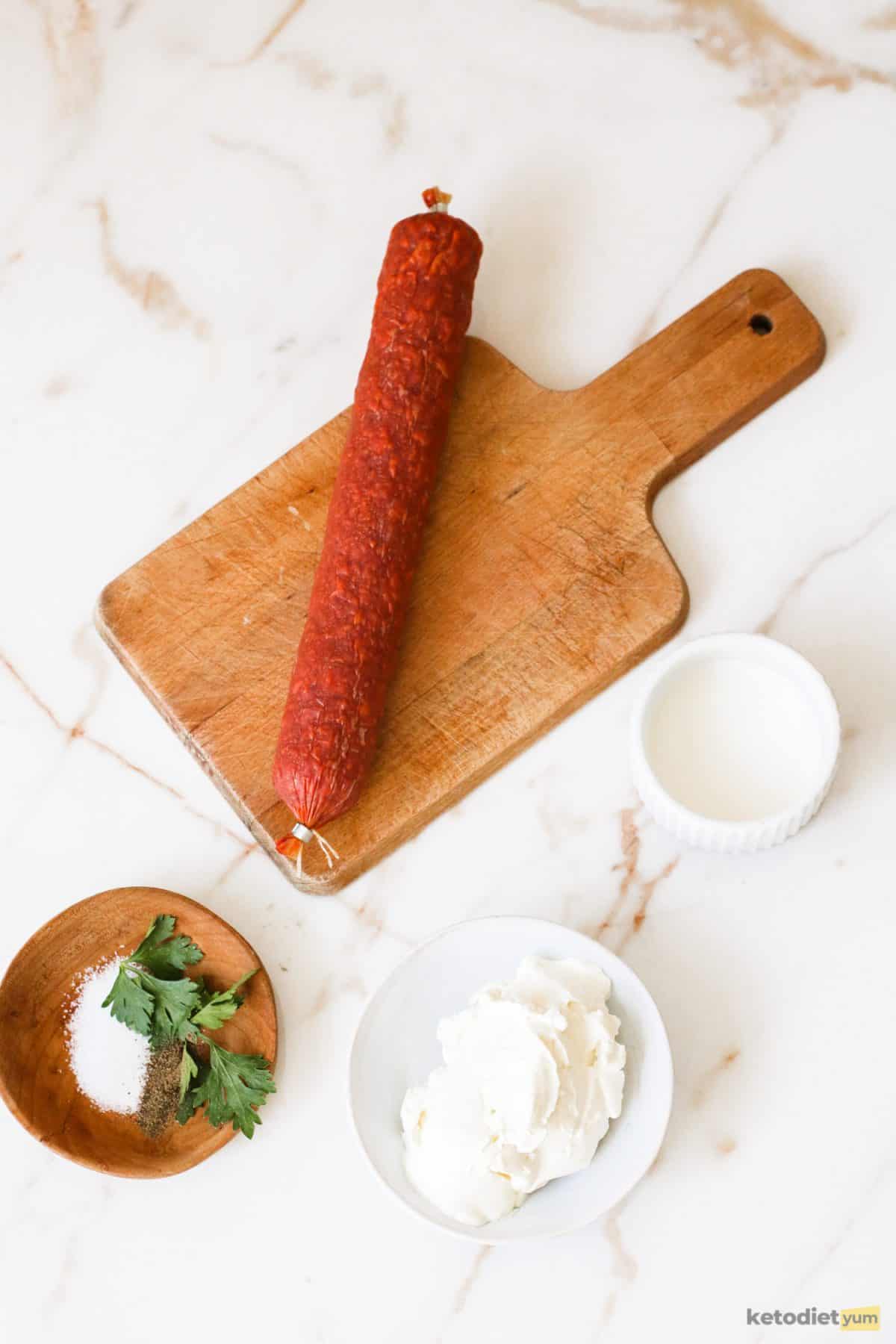 Ingredients arranged on a table including chorizo, cream cheese, heavy cream, herbs and seasonings