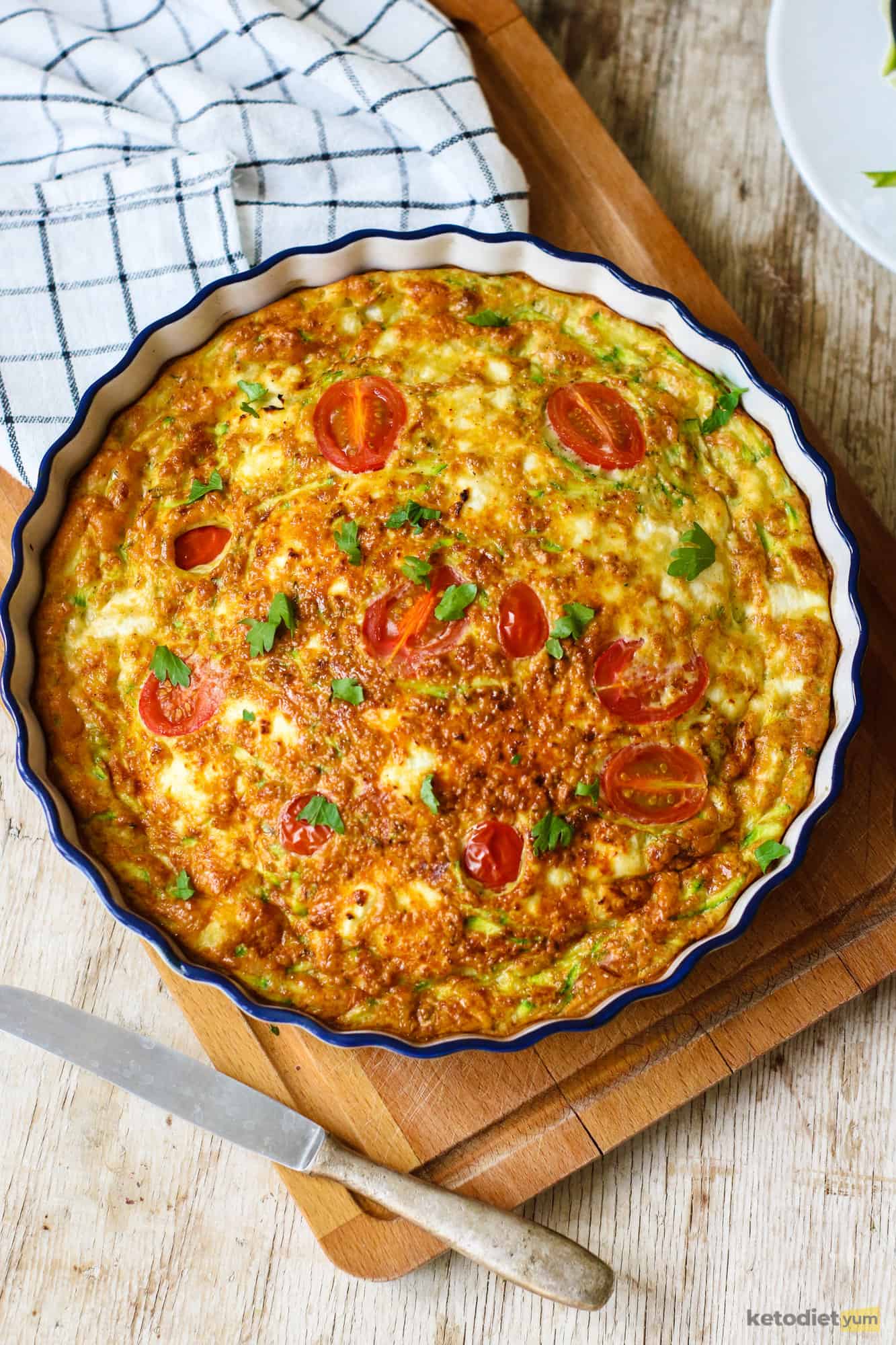 A keto frittata made with zucchini, goat cheese and cherry tomatoes in a baking dish