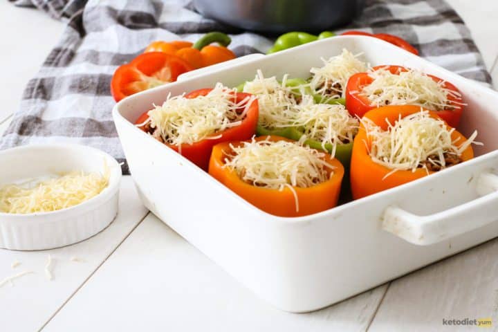 Stuffed bell peppers topped with Edam cheese in a baking pan ready to bake