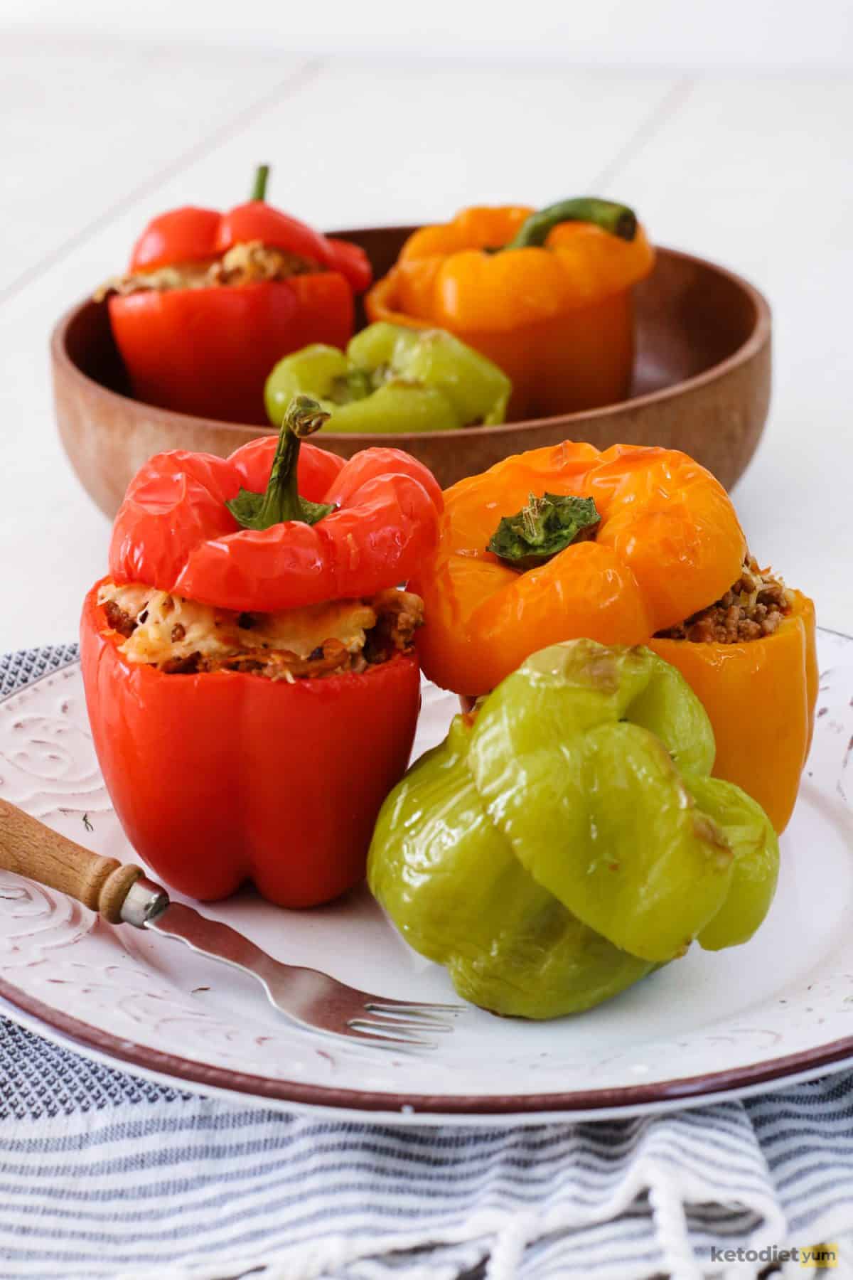 Stuffed bell peppers on a plate filled with ground beef, cauliflower rice and topped with melted cheese