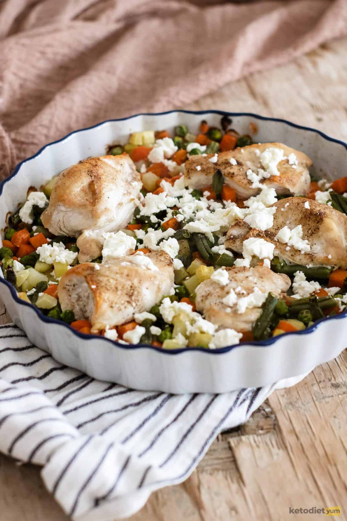 Adding crumbled feta cheese to roasted chicken and vegetables before returning it to the oven to bake