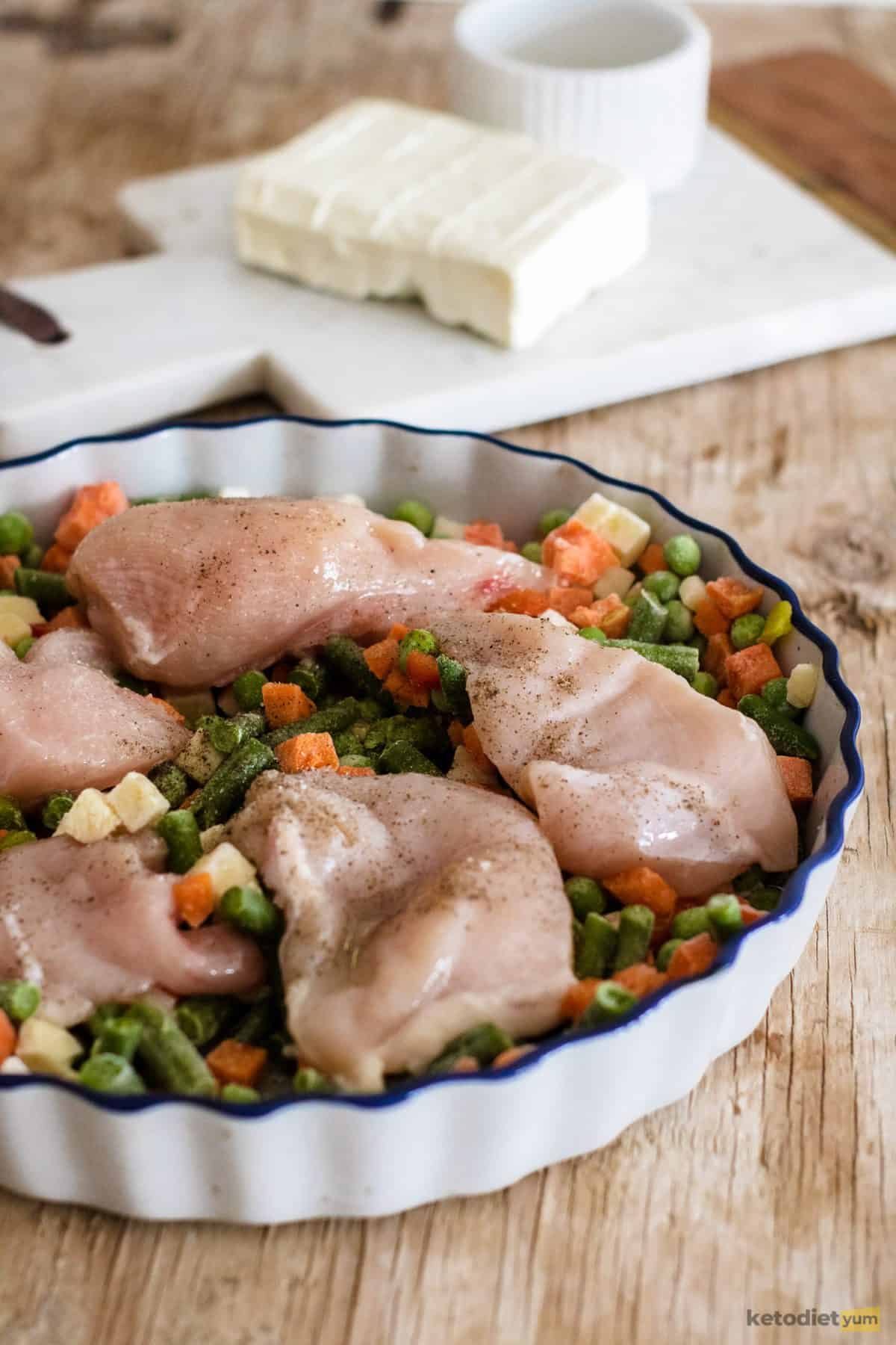 Chicken breasts and frozen mixed veggies placed in a baking tray and drizzled with vegetable oil