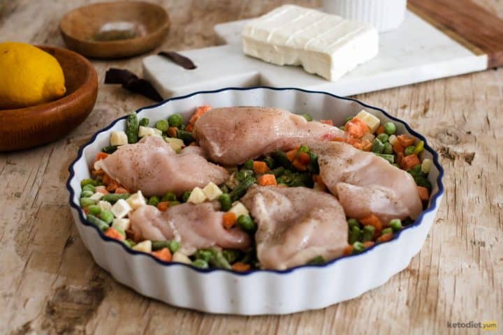 Chicken breasts and frozen mixed veggies in a baking tray seasoned with salt, black pepper and drizzled with vegetable oil