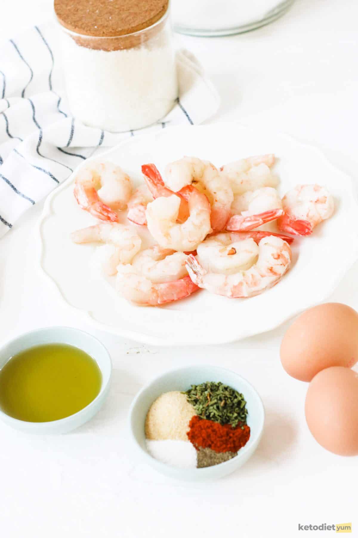 Ingredients arranged on a table including shrimp, eggs, avocado oil, shredded coconut and seasonings