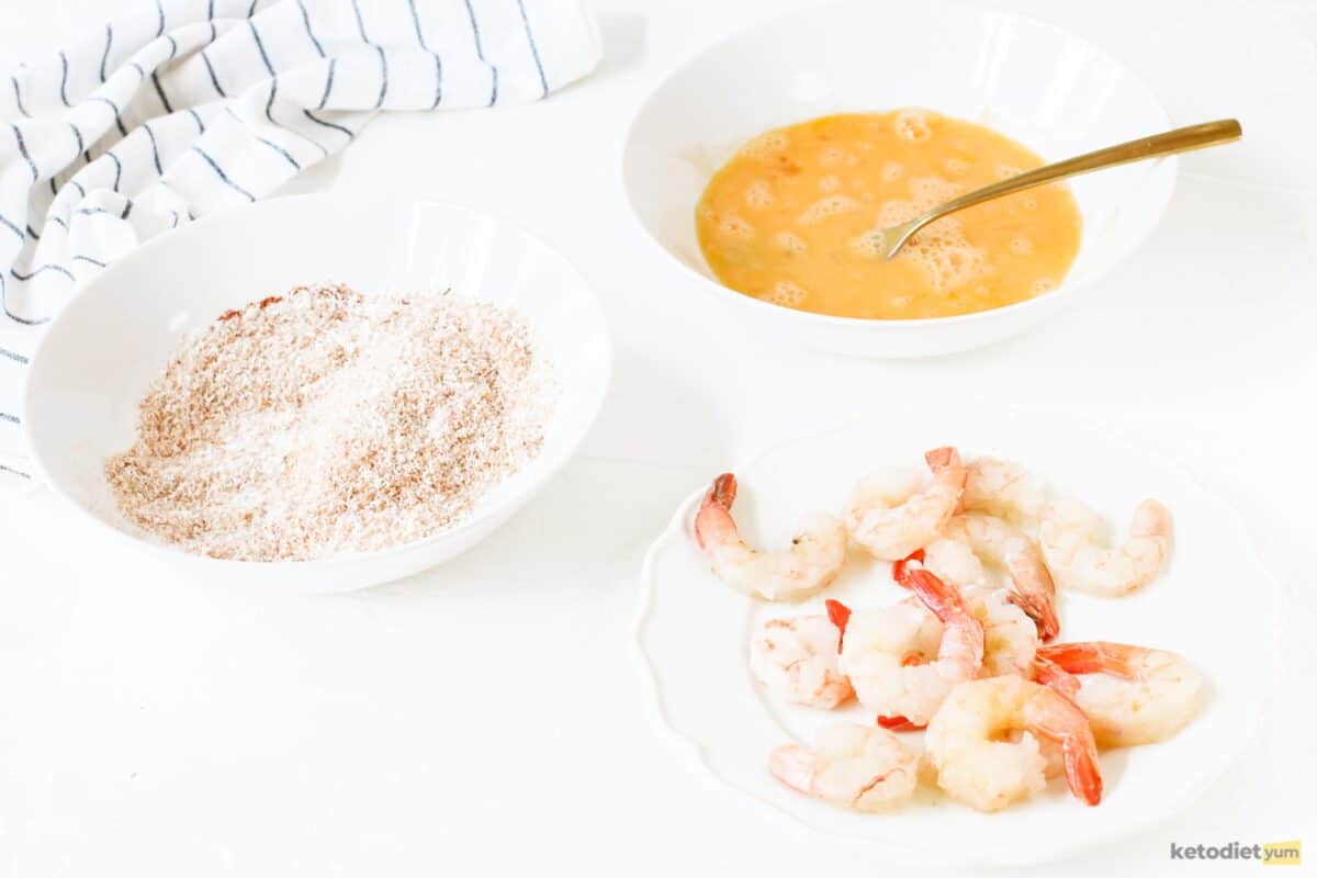 Mixing bowls with whisked eggs and seasoned shredded coconut ready to dip and coat shelled and deveined shrimp