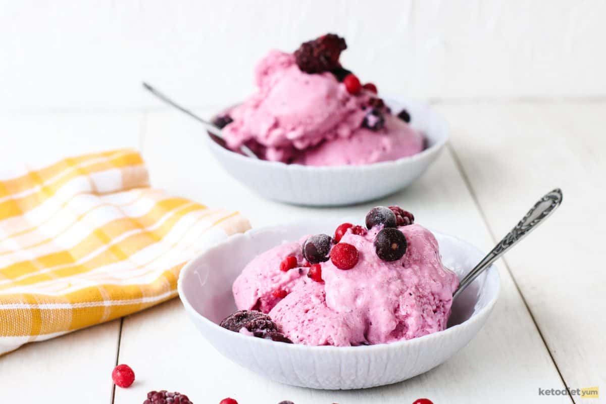 Keto frozen yogurt topped with forest fruit and served in white bowls on a table