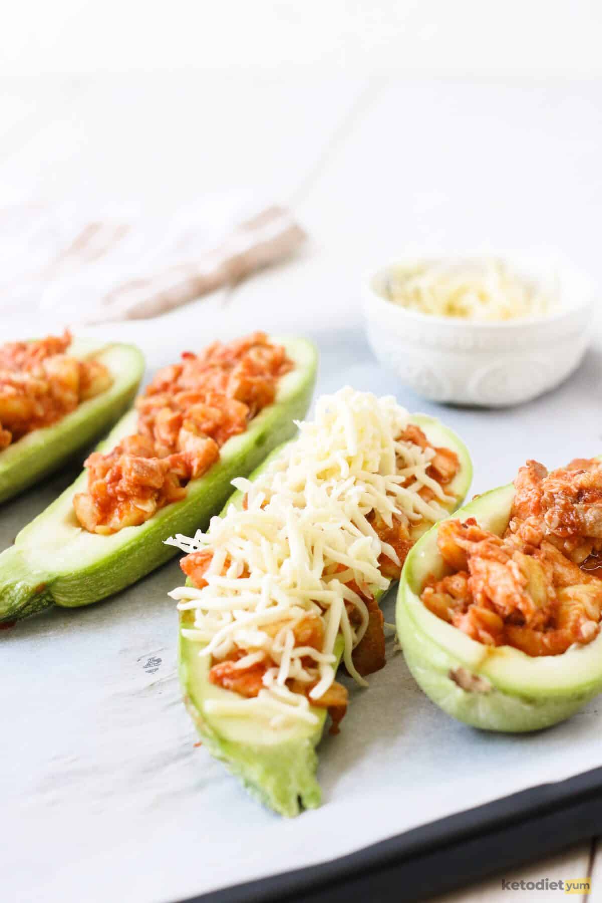 Zucchini boats filled with salmon and topped with mozzarella cheese ready to bake