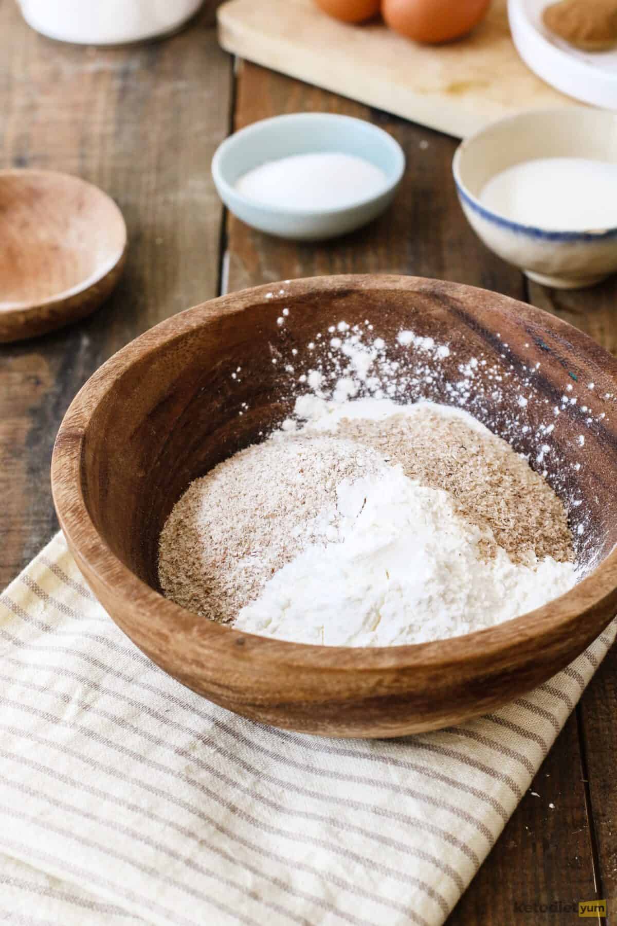 Preparing dry ingredients in a mixing bowl including almond flour, coconut flour, baking powder, psyllium husk and xanthan gum