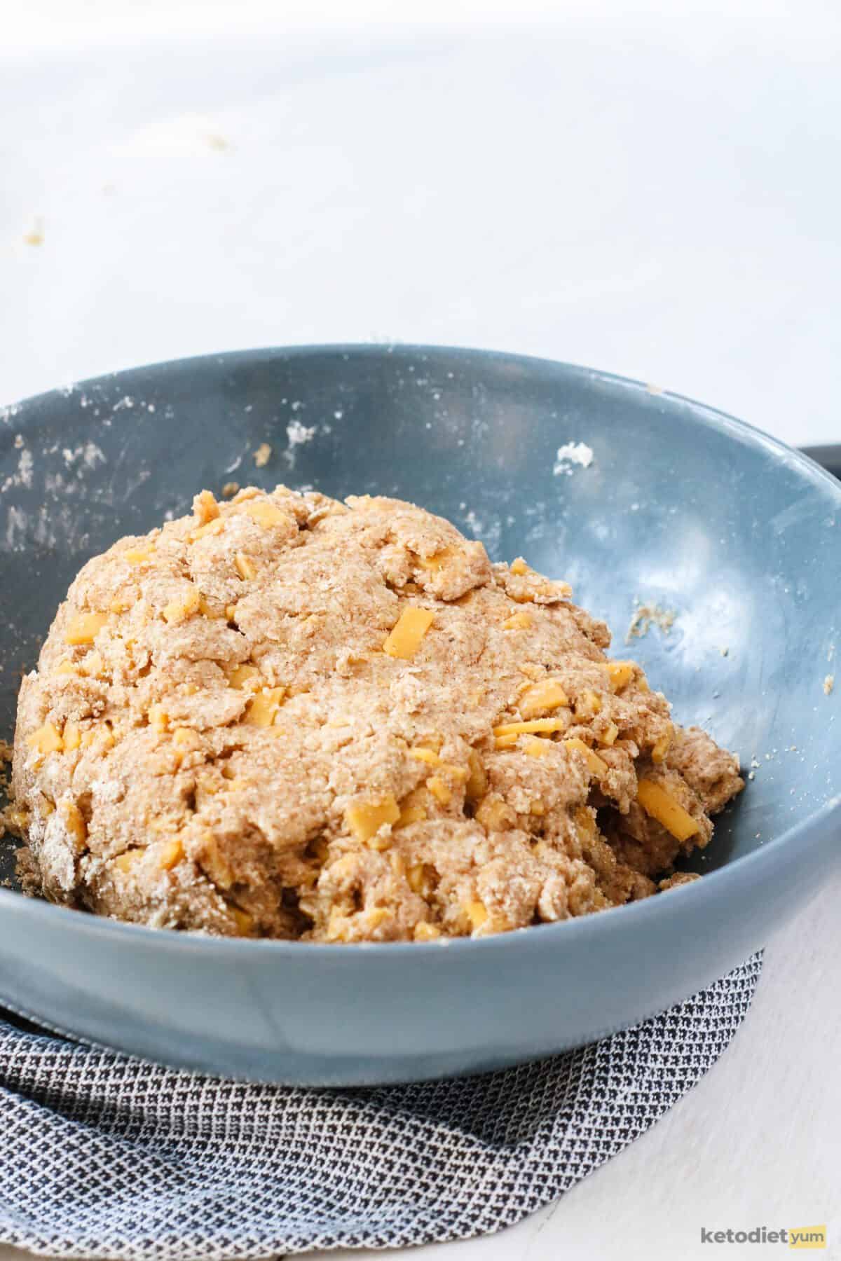 Combining the almond flour, xanthan gum, garlic powder, baking soda, salt, cheddar cheese and whisked eggs to make a keto cheddar biscuit dough