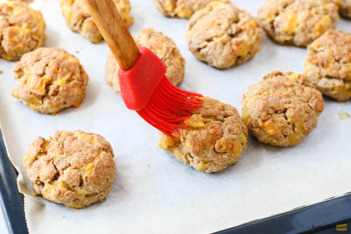 Brushing the keto cheddar biscuits with the garlic butter coating before returning to the oven until golden brown