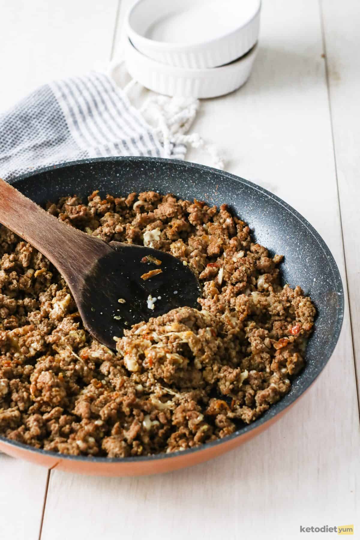 Sautéing ground beef seasoned with salt, pepper, mustard powder and garlic powder in a frying pan over a medium-high heat