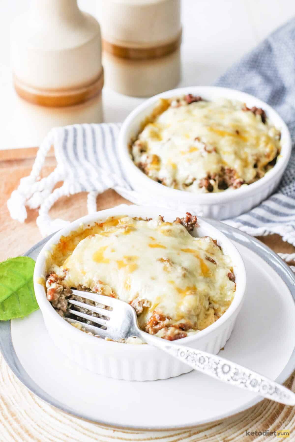 Delicious mini keto cheeseburger pies served in small baking trays topped with golden cheese