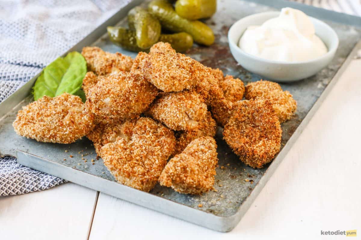 Delicious keto chicken nuggets coated with crispy pork rinds and served with dill pickles and mayonnaise