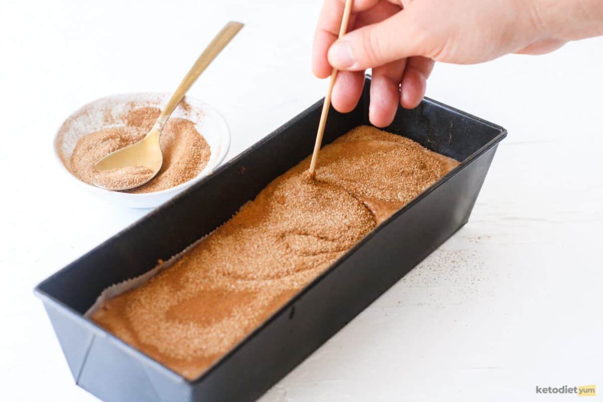 Using a skewer to create a cinnamon swirl marble effect in our keto cinnamon cake batter before baking