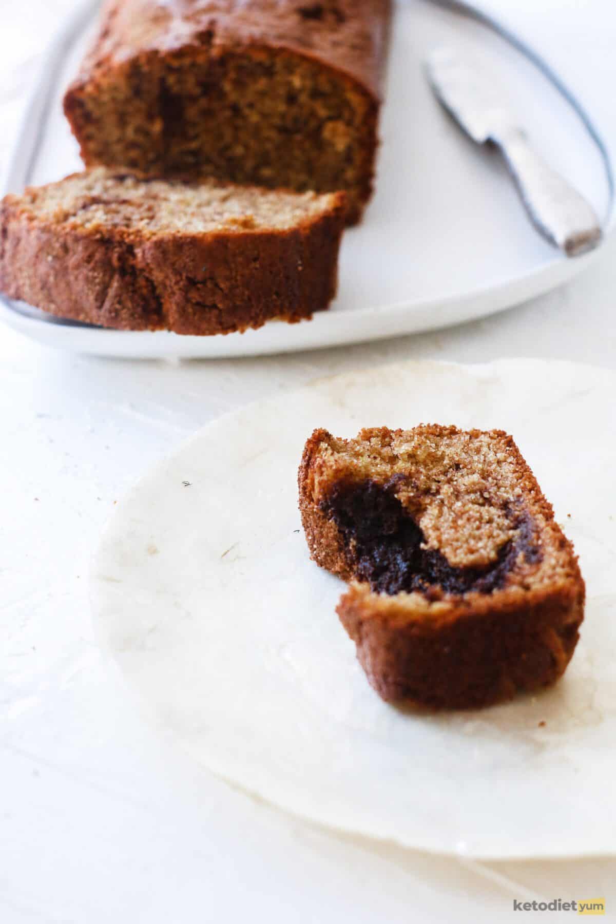 A delicious slice of keto cinnamon swirl cake on a white plate showing the gooey cinnamon swirl center