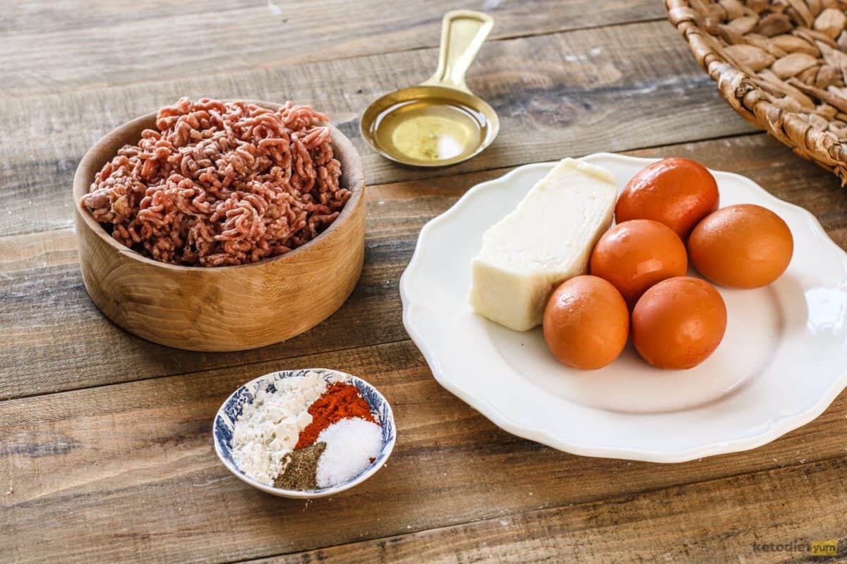 Ingredients arranged on a table to make keto Scotch eggs including ground pork, eggs, almond flour, sunflower oil, smoked paprika, salt and black pepper