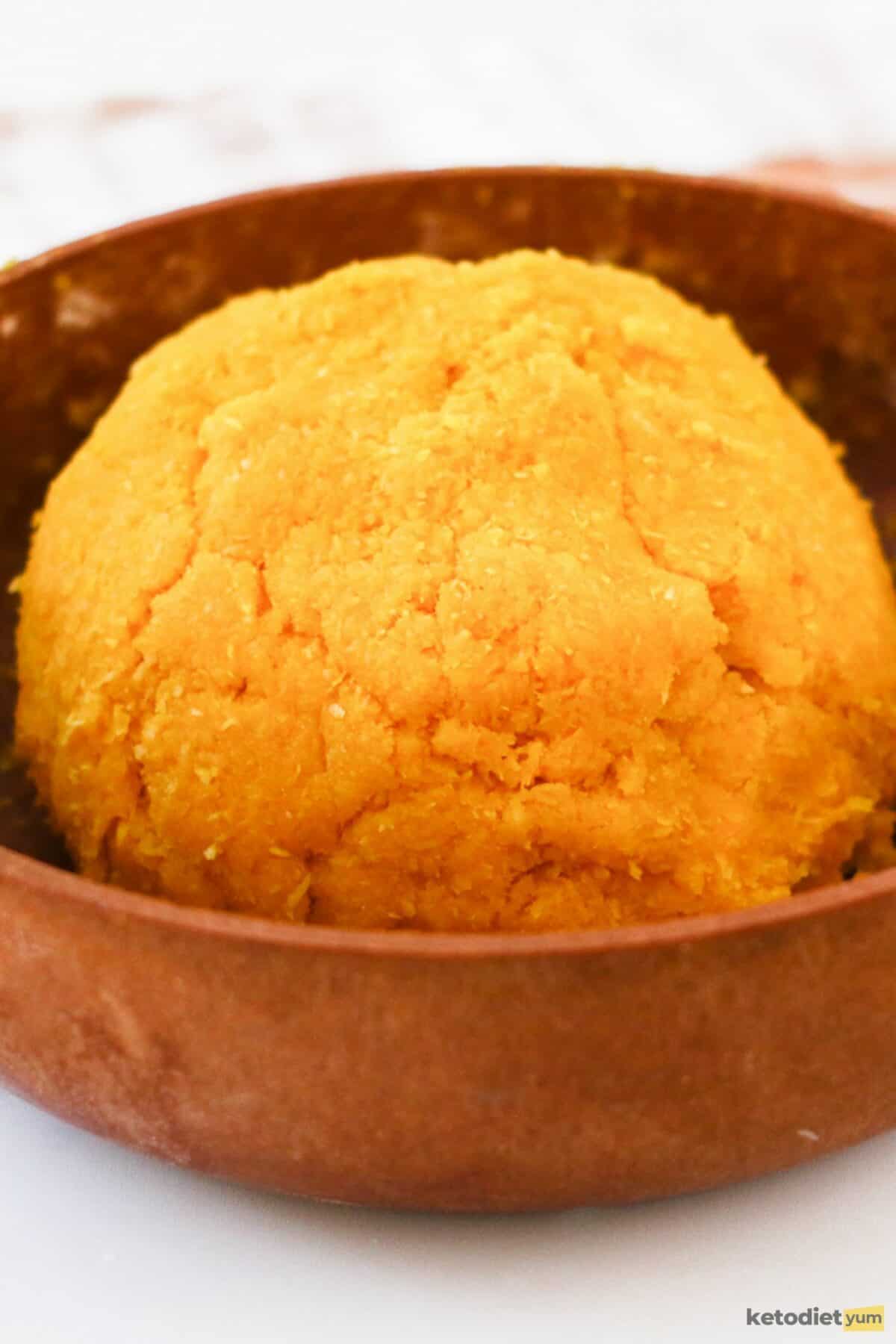 Brown bowl with orange dyed marzipan dough on a table