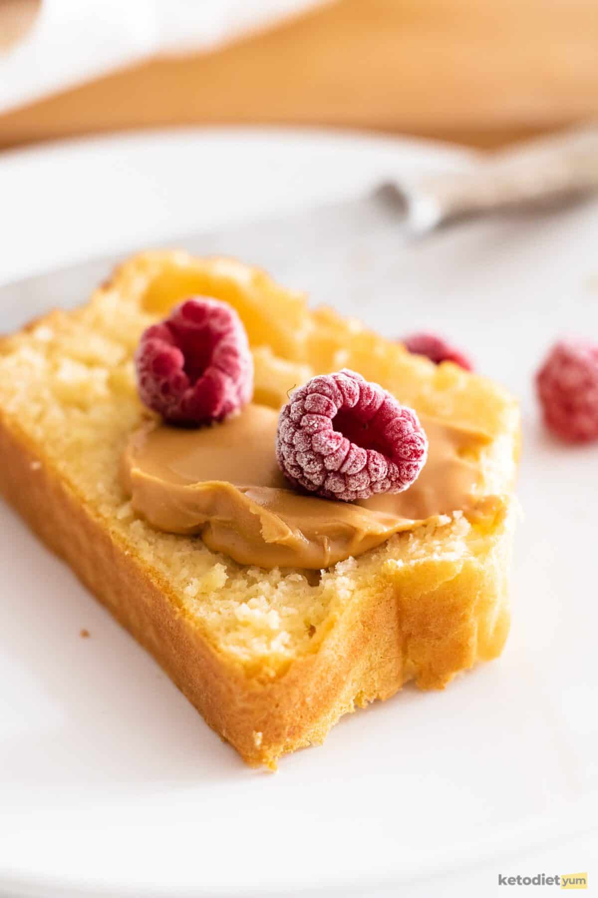 Slice of toasted white bread with a dollop of peanut butter and two frozen raspberries