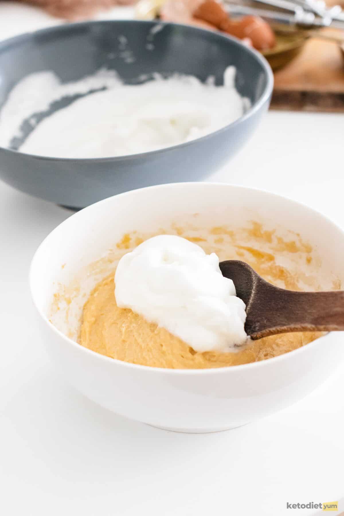 Two bowls on a table with a spoon of meringue over the bowl filled with batter