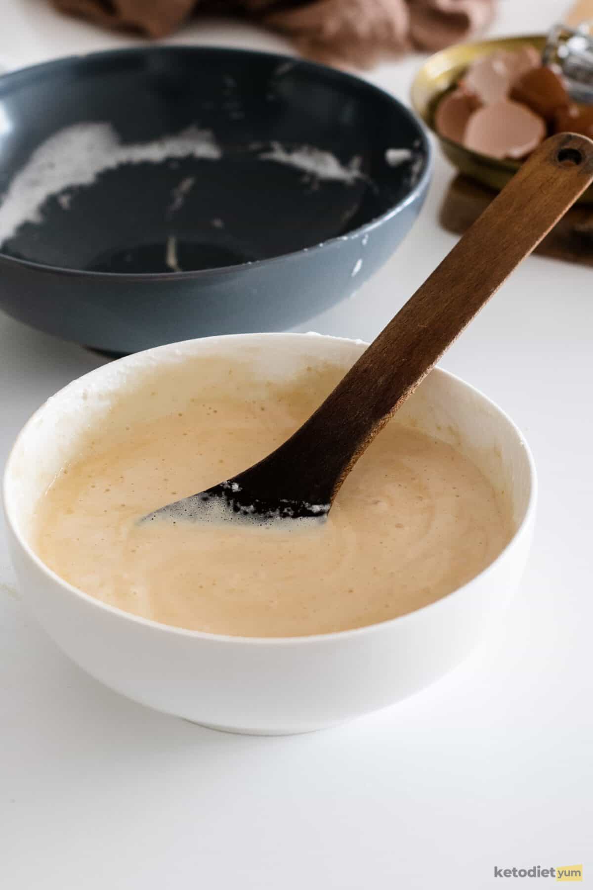 White bowl with a spoon and batter inside with another empty dark blue bowl in the background