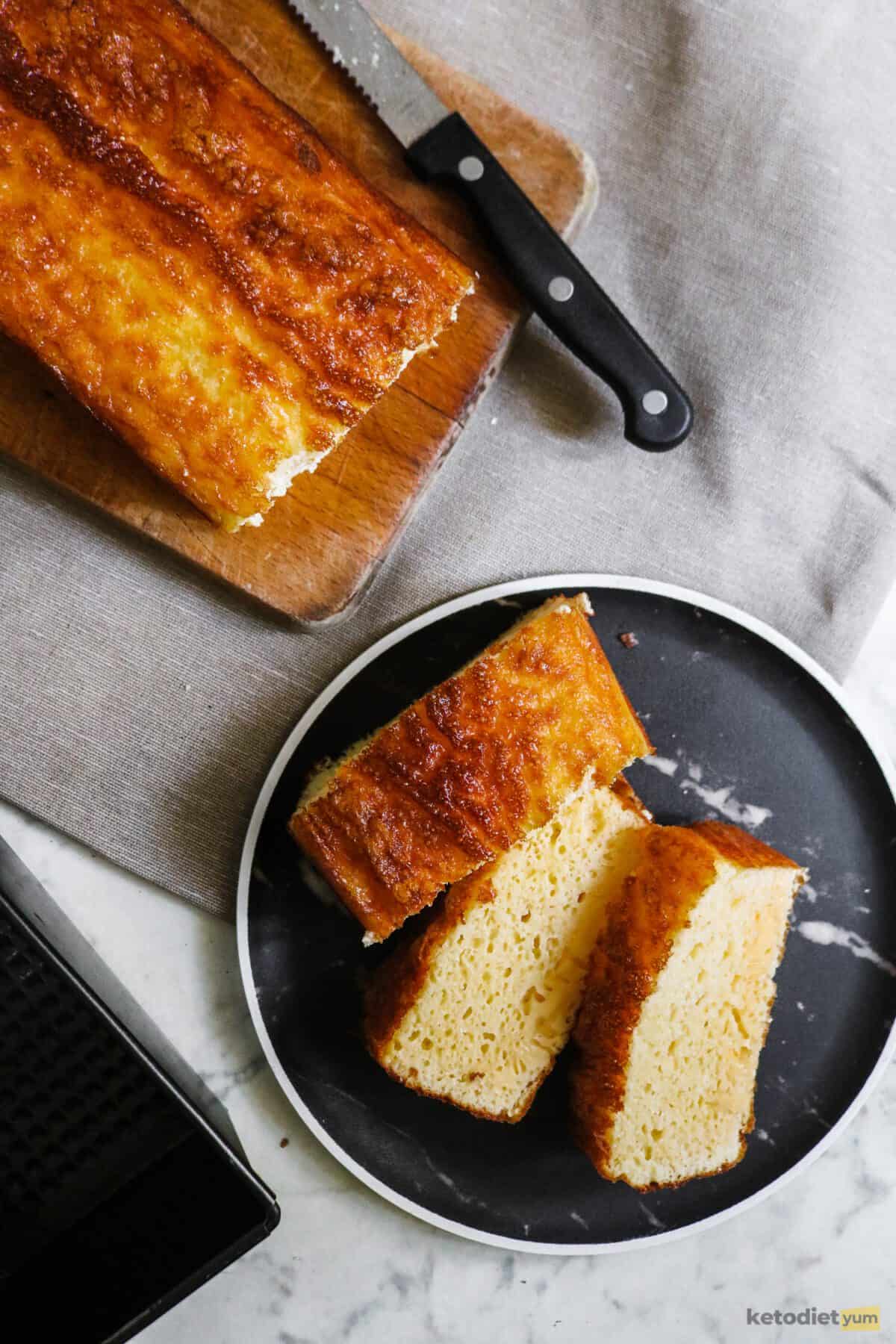 3 slices of egg loaf on a black plate with the unsliced egg loaf and a knife in the background