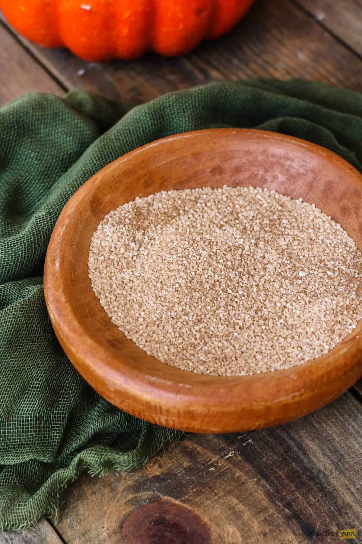 Small brown bowl with granulated Erythritol and ground cinnamon on a table