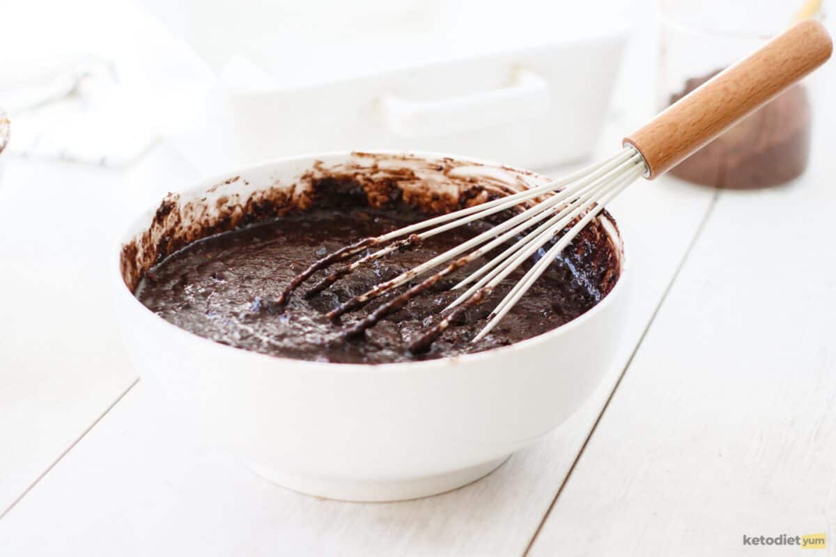 Brownie batter and a whisk in a white bowl on a table