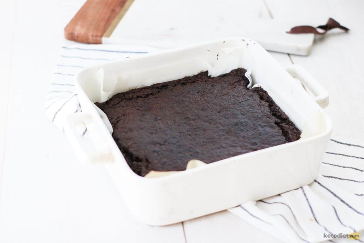 A white baking pan filled with baked brownie on a white table
