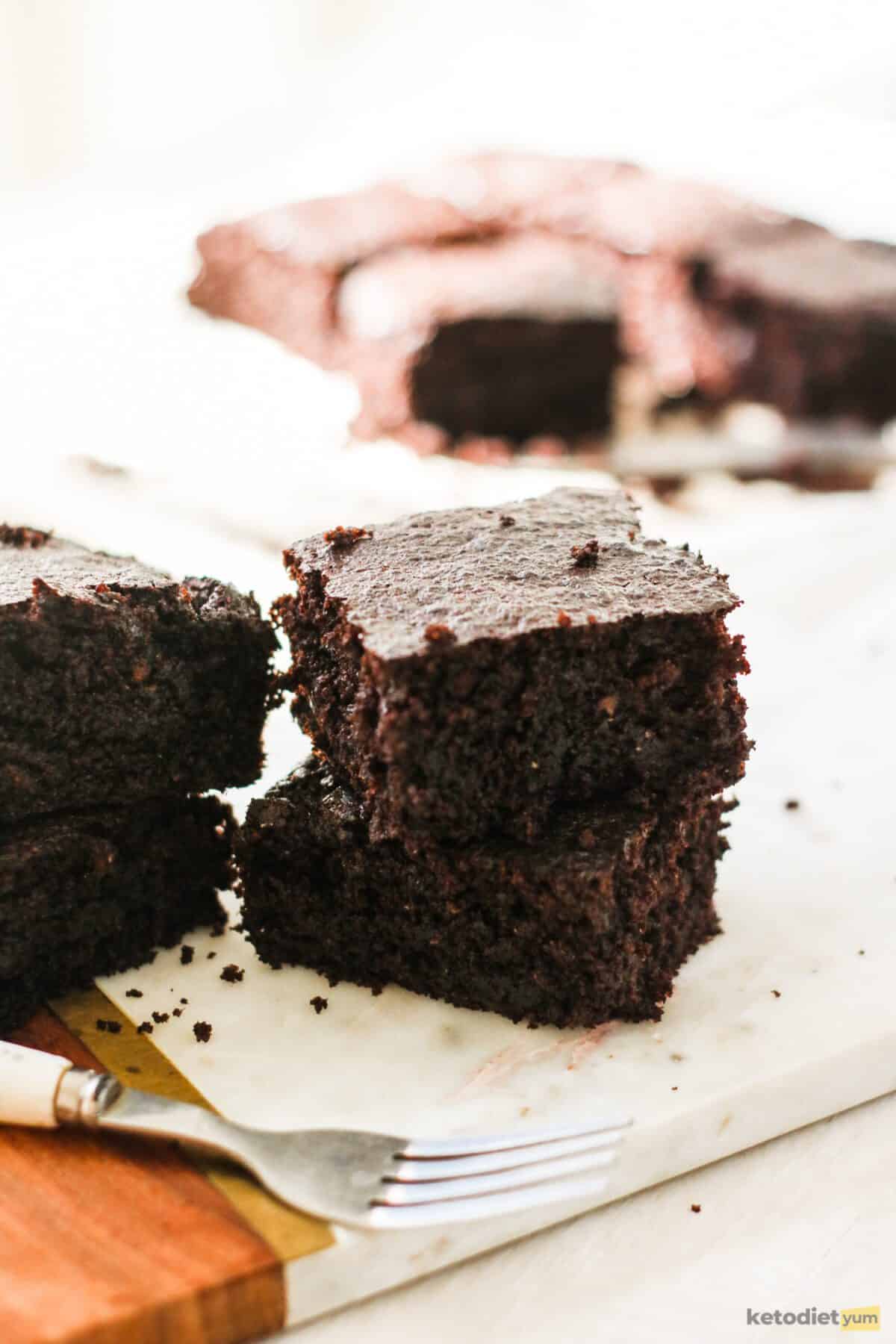 Brownie squares stacked on a chopping board with a fork