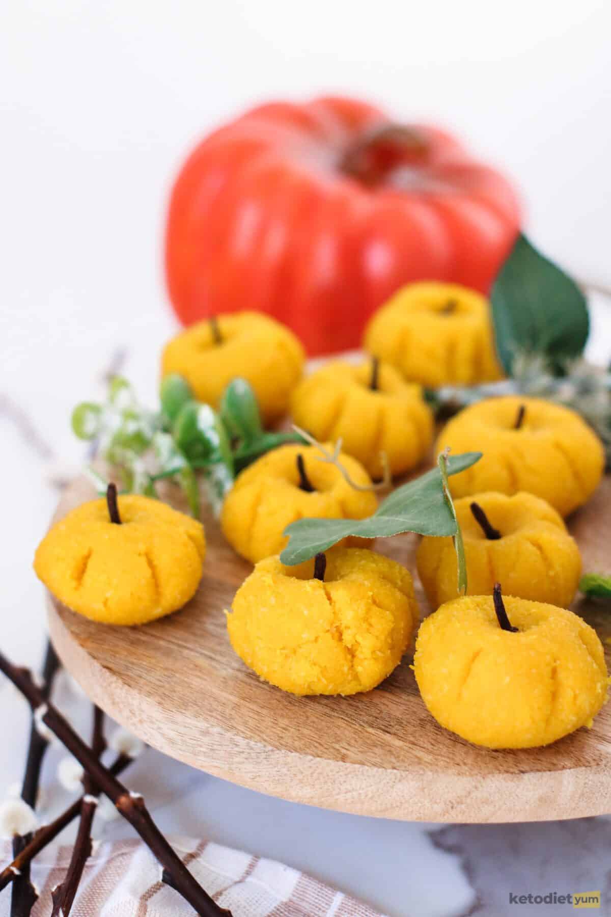 8 marzipan pumpkins on a serving board with a pumpkin in the background