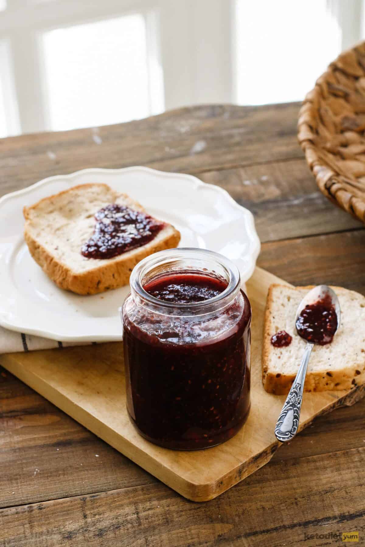 Raspberry chia jam in a glass jar spread on low carb bread