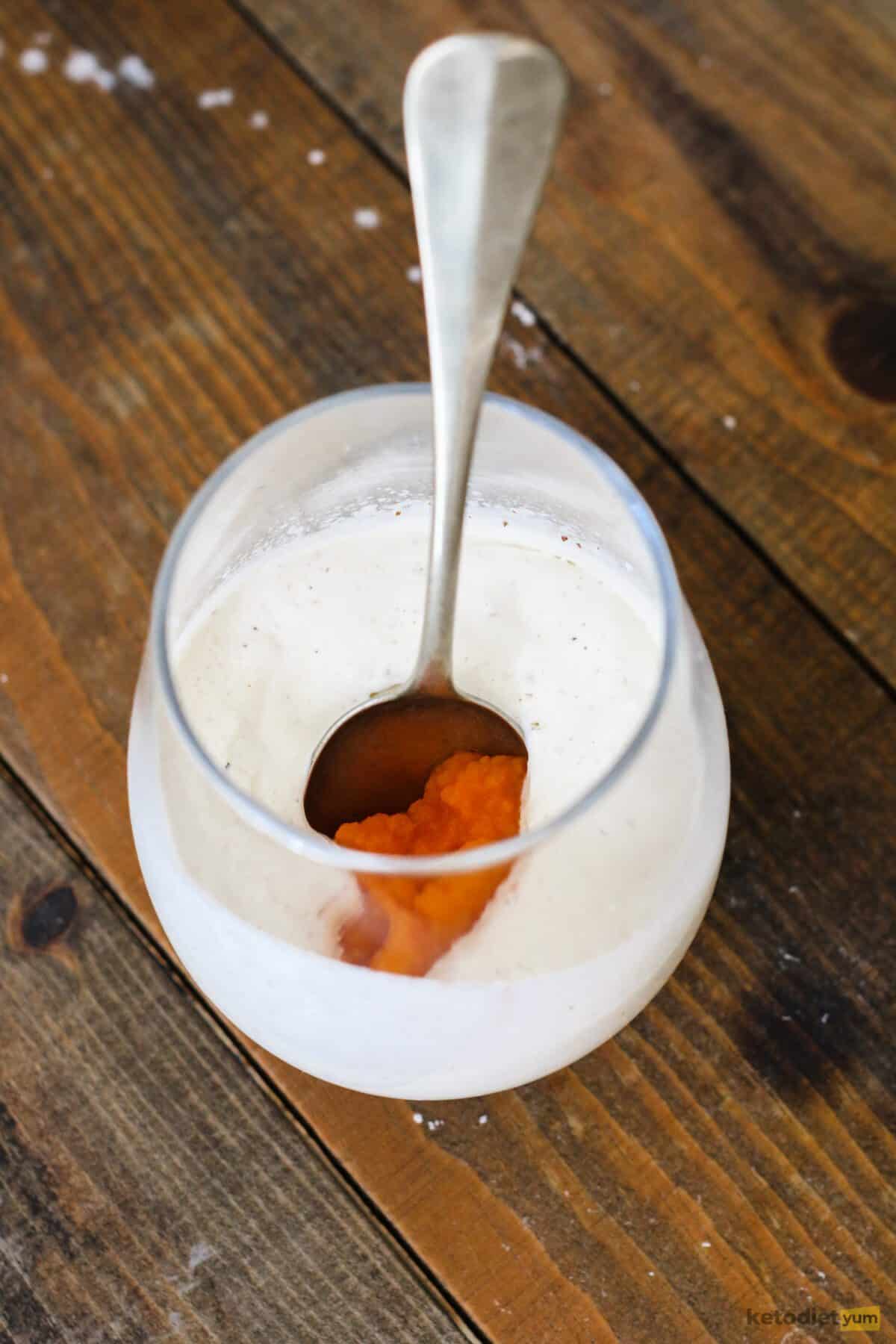 Adding pumpkin puree to a mixing glass filled with heavy cream mixture