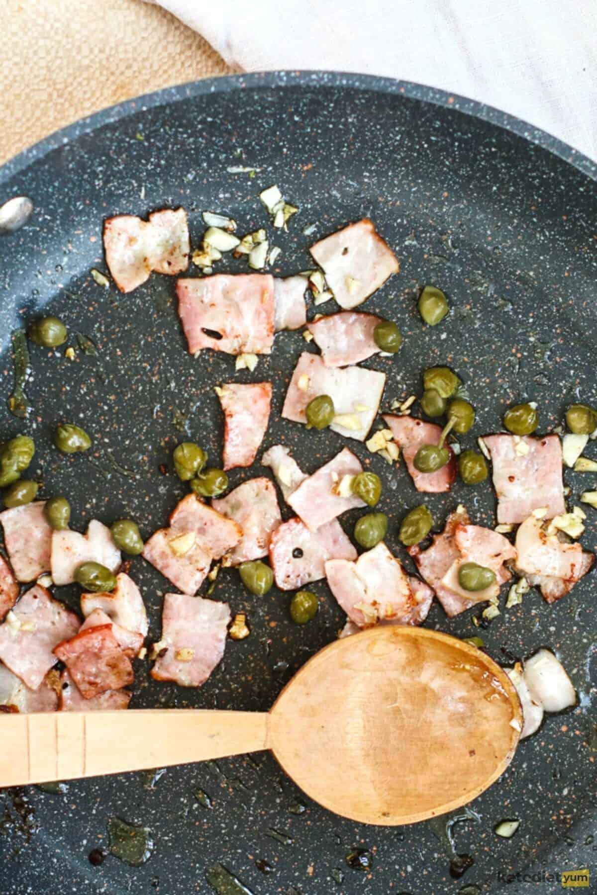 Frying bacon, garlic and capers in olive oil