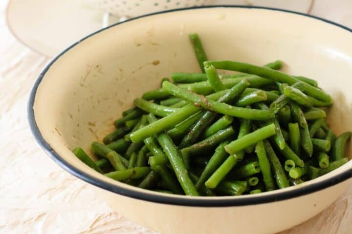 Green beans washed and seasoned with salt and black pepper in a bowl
