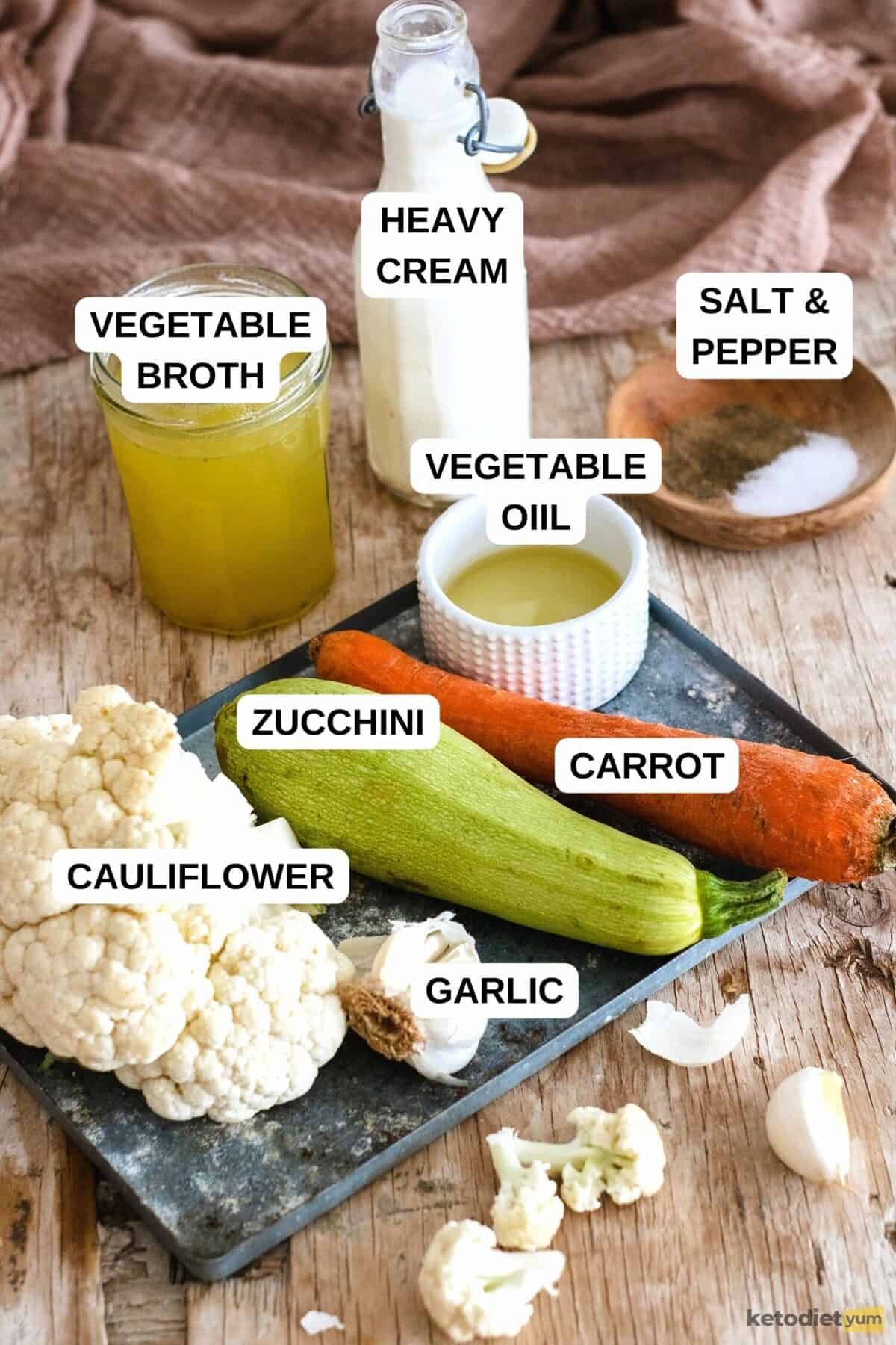 Oven tray with cauliflower, garlic, zucchini and carrot, with jars, bottles and bowls on a wooden table