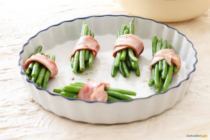 Green beans wrapped with bacon in a baking dish ready to bake