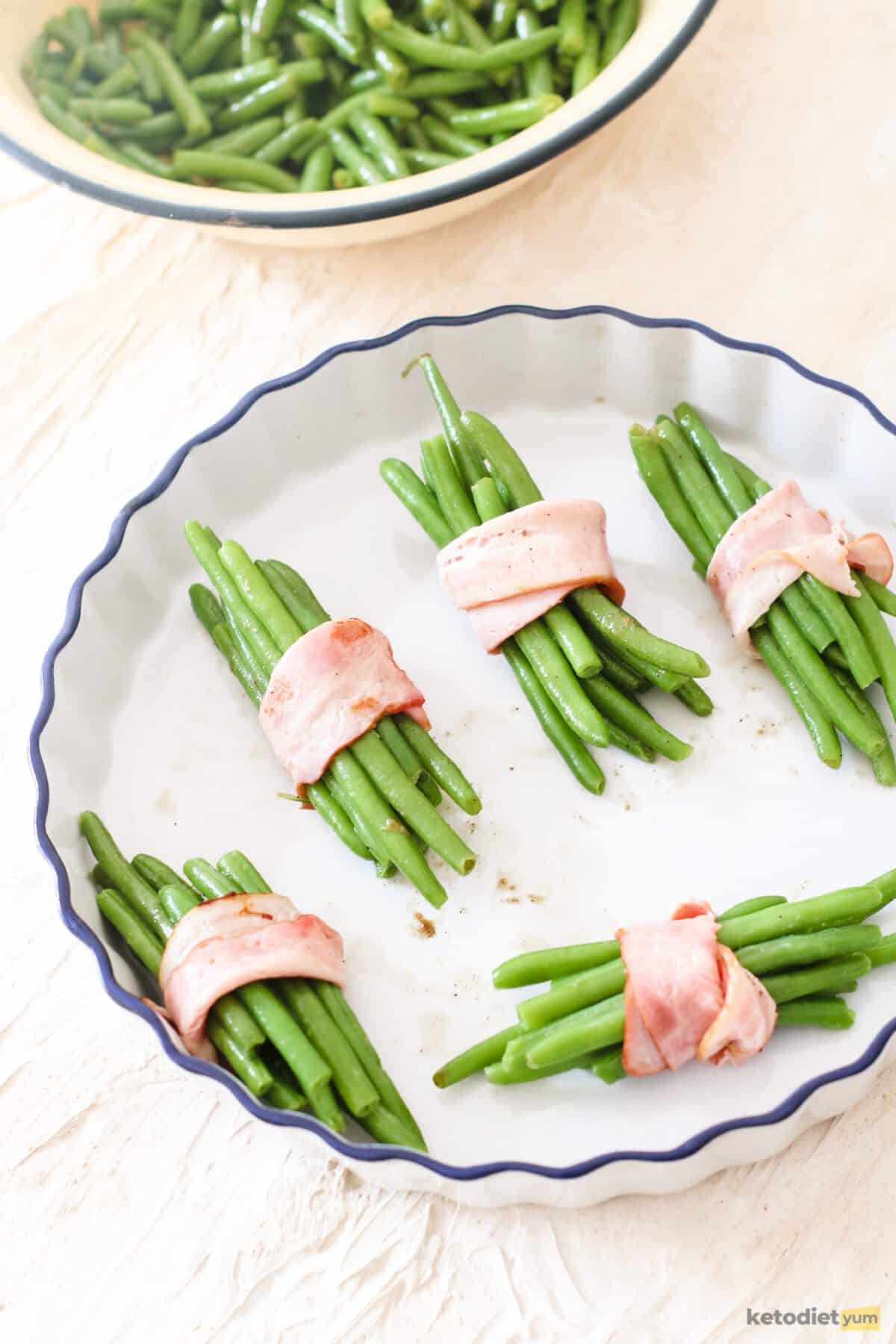 Green beans wrapped with bacon in a baking dish ready to bake