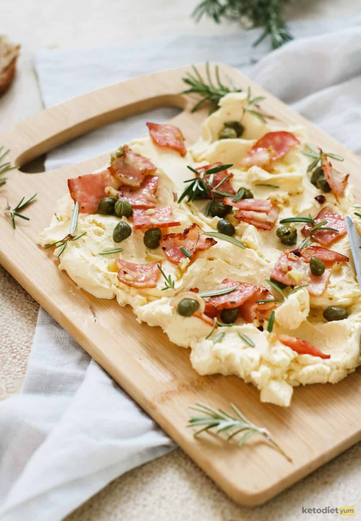 Keto butter board topped with crispy bacon, capers, garlic and rosemary