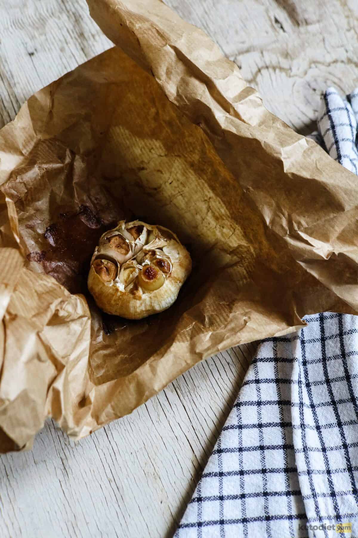 Garlic head in baking paper roasted until golden, soft and juicy