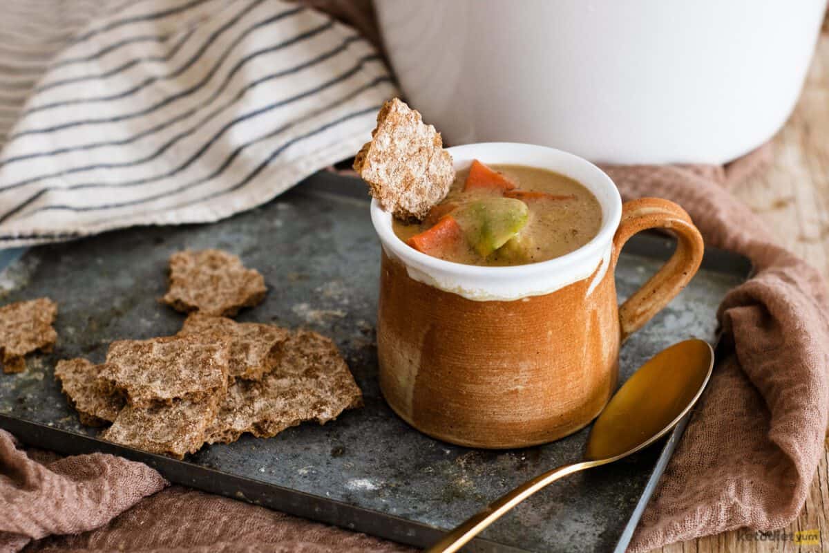 Cup of soup on a oven tray with crackers and a spoon