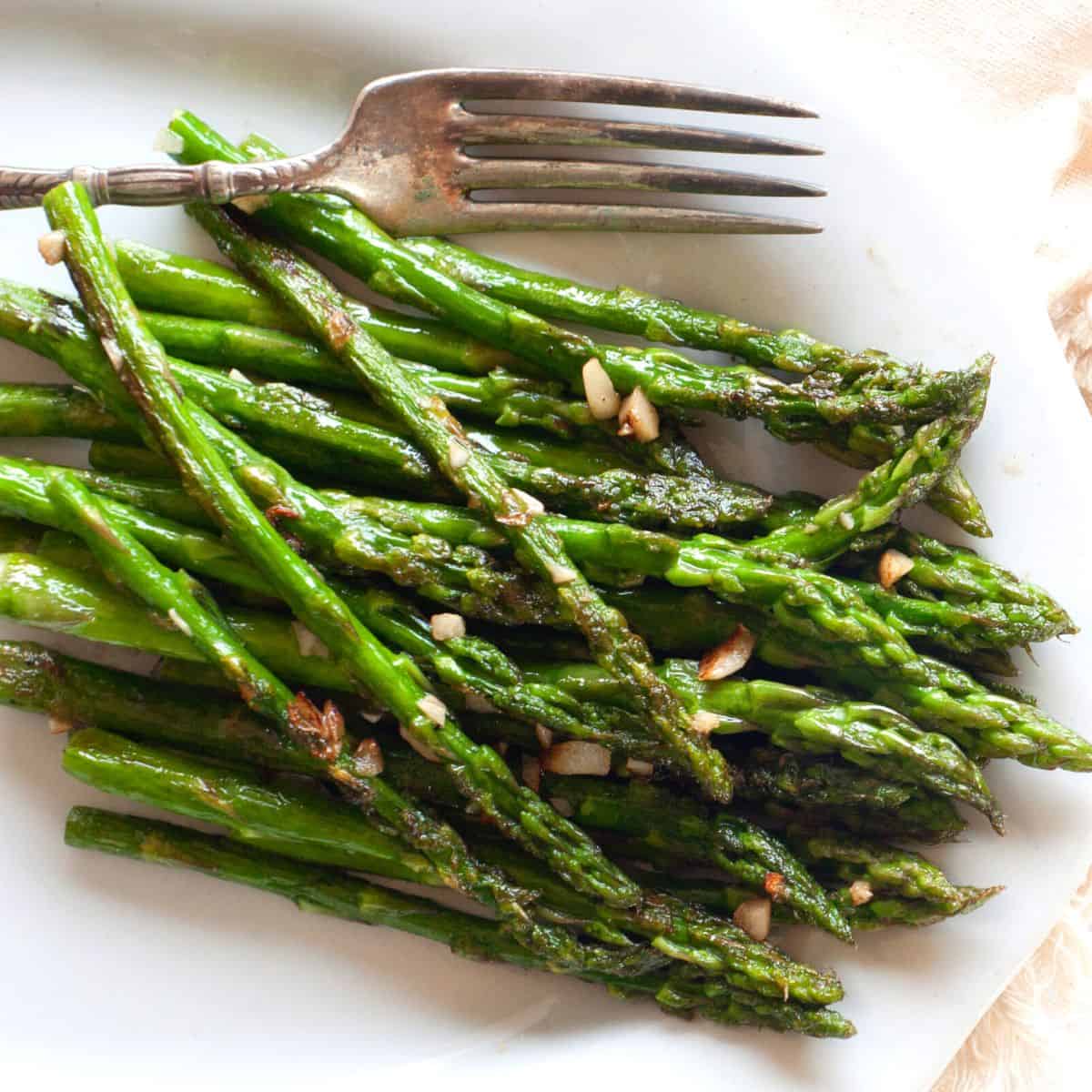 cooked asparagus on a plate with a fork