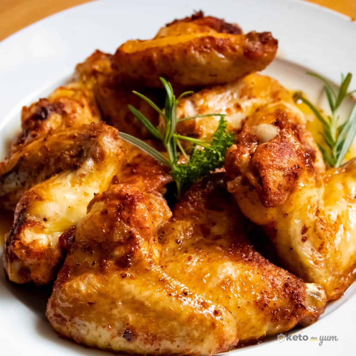 Carnivore Diet for Beginners: Easy Guide & 21-Day Meal Plan Golden roasted chicken wings served on a white plate with fresh herbs, showing an easy and flavorful carnivore friendly meal for beginners.