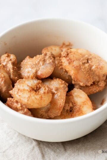 Carnivore Cajun Shrimp Creamy Cajun shrimp served in a white bowl on a neutral cloth napkin, an easy 10-minute low carb dinner idea.