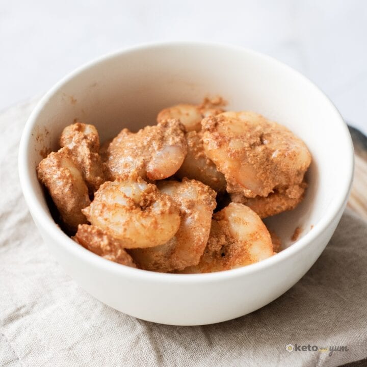 Creamy Cajun shrimp served in a white bowl on a neutral cloth napkin, an easy 10-minute low carb dinner idea.