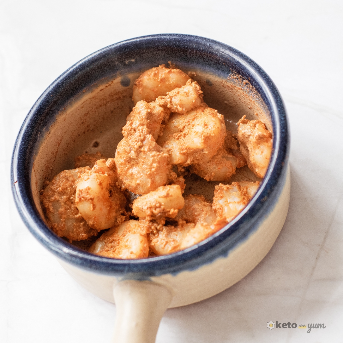 Close-up of creamy Cajun shrimp in a small ceramic pot, coated in spicy sauce for a simple 3 ingredient Cajun shrimp recipe.