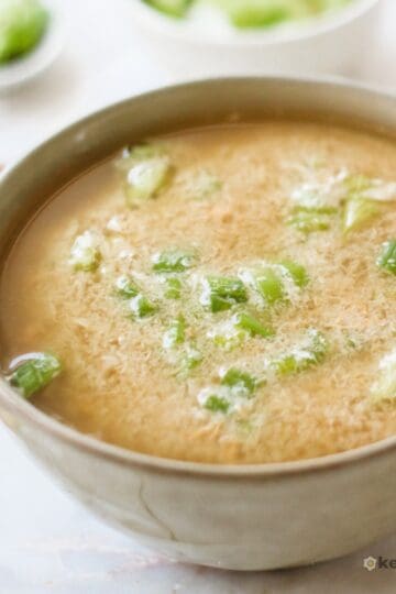 14 High Protein Low Carb Soups (Easy & Hearty Recipes) Warm keto egg drop soup topped with chopped green onions in a beige ceramic bowl, showing a light, savory broth that’s high in protein and low in carbs.