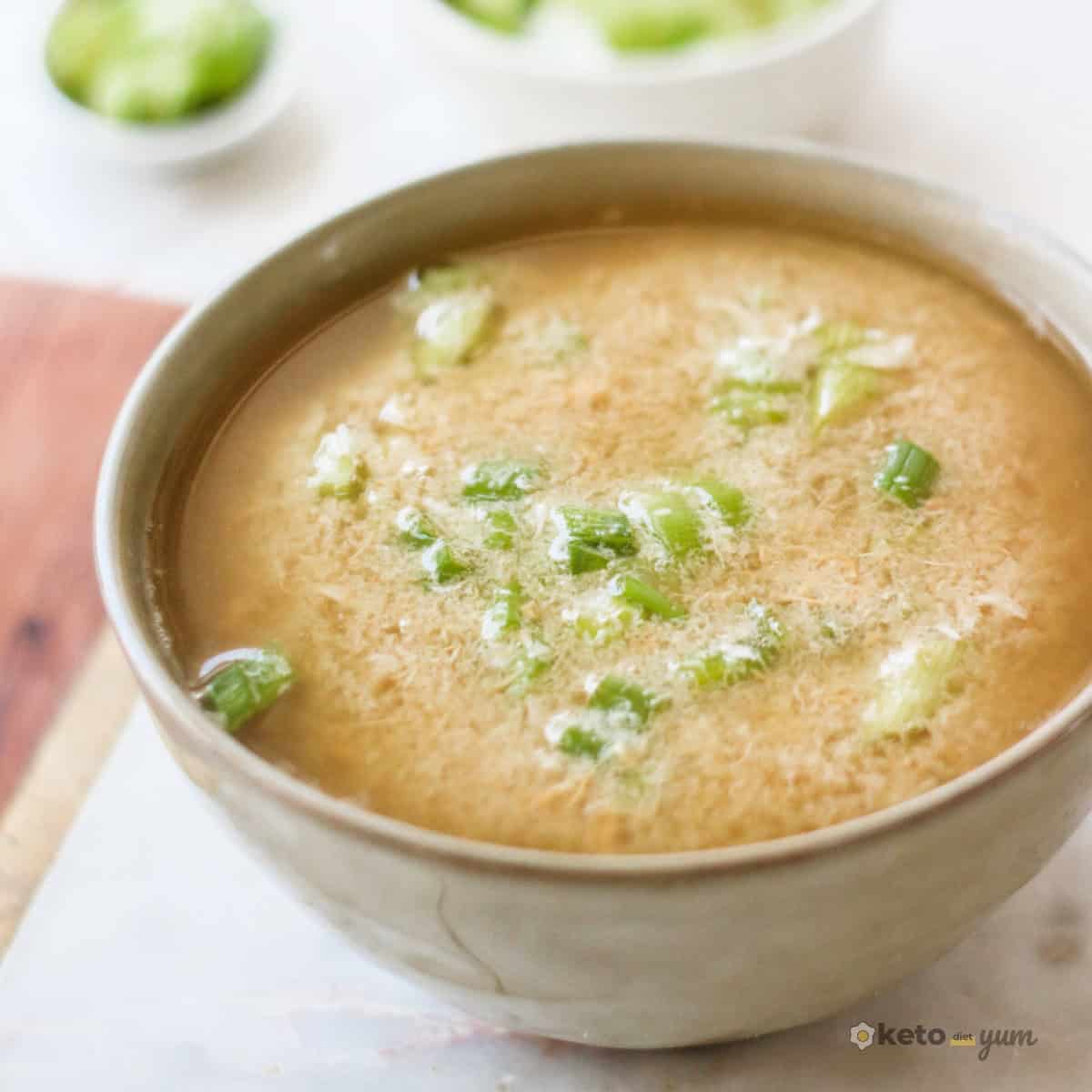 14 High Protein Low Carb Soups (Easy & Hearty Recipes) Warm keto egg drop soup topped with chopped green onions in a beige ceramic bowl, showing a light, savory broth thatβs high in protein and low in carbs.