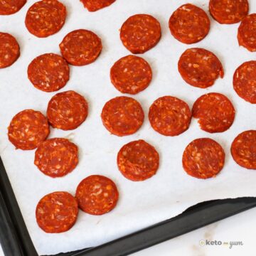 Sheet pan lined with baking paper topped with evenly spaced baked chorizo chips that are crispy and bright red. A simple high protein, zero carb keto snack option.